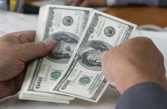 A customer counts dollar notes at a bank in Hanoi, Vietnam.