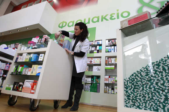 A pharmacist arranges drugs inside a pharmacy in Athens.