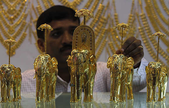An employee displays gold models of elephants at the Gem and Jewellery India International Exhibition 2013 in Chennai.