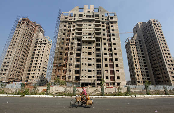 A man cycles past residential buildings under construction in Kolkata.