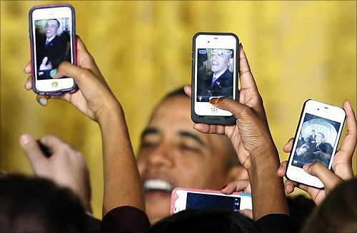 Attendees photograph President Barack Obama with their mobile phones at a Women's History Month reception at the White House in Washington.