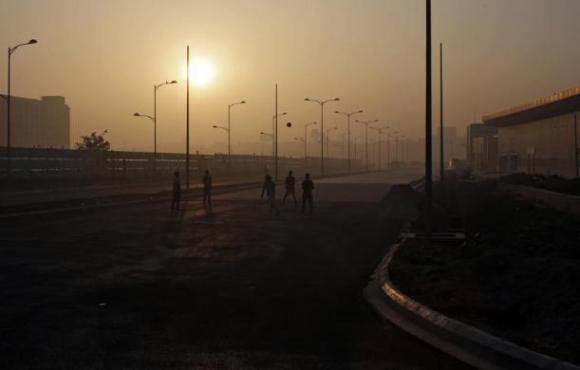 Youths play with a ball in front of hotels being constructed outside the Indira Gandhi International Airport in New Delhi.