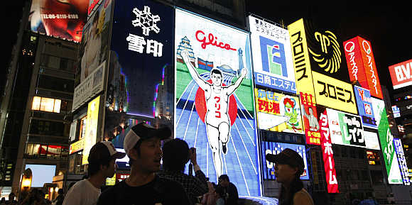 Passers-by are silhouetted against advertisements in the Dotonbori shopping and amusement district in Osaka, western Japan.