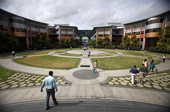 Employees walk in a forecourt at the Infosys campus in the Electronic City area of Bangalore.