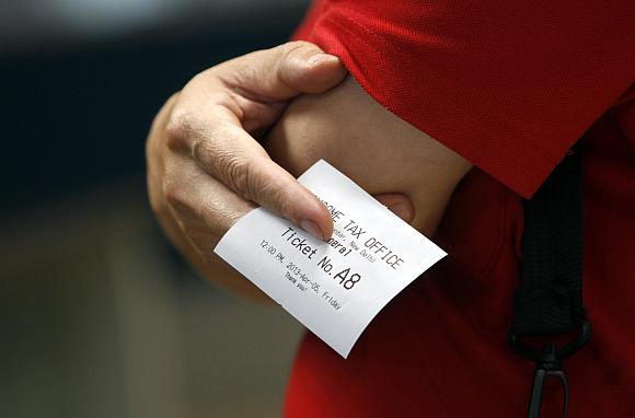 A man holds a slip of paper with the queue number as he waits to speak with an official inside the Income Tax office in New Delhi.
