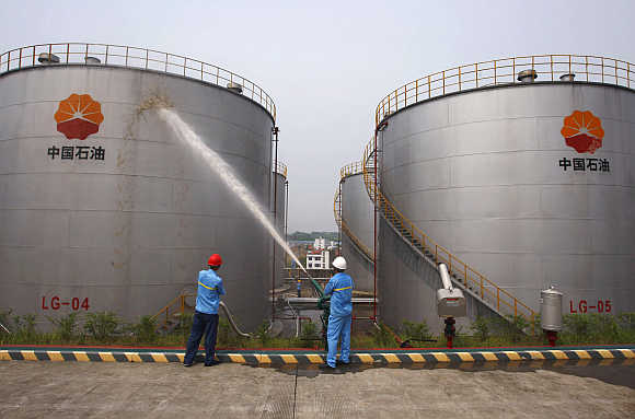 Employees spray water to cool down oil tanks at a storage facility belonging to PetroChina oil, in Suijing, Sichuan Province, China.