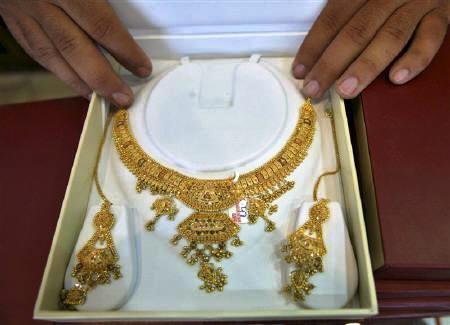 A shopkeeper displays gold jewellery inside his showroom.