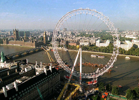 London Eye, a giant ferris wheel, dominates the South Bank of the River Thames as it towers above Big Ben and the Houses of Parliament.