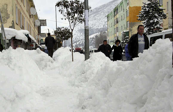 People walk after snowfall in the city of Bulqize, some 140km north of capital Tirana in Albania.