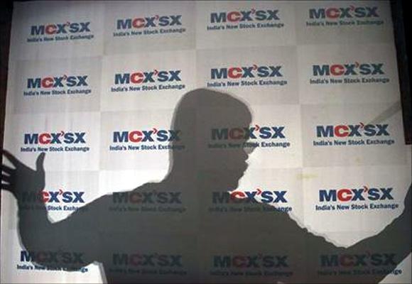 A man moves an advertising poster bearing the MCX-SX logo at their Exchange Square building in Mumbai. 