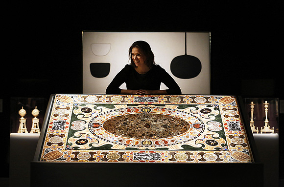 A Sotheby's employee poses with William Scott's Permutation 3 - White (top) and a Late Renaissance Antique Marble Inlaid Table Top at Sotheby's Auction House in London.