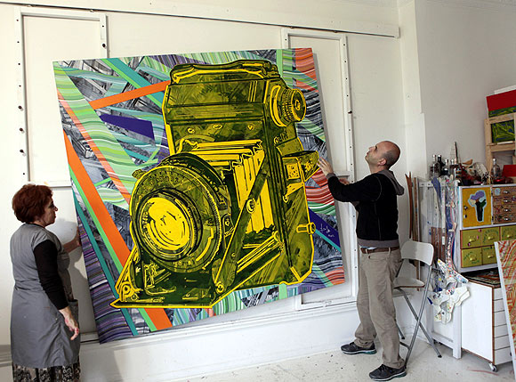 Turkish artist Yigit Yazici (R) fixes one of his artworks at his studio in Istanbul.