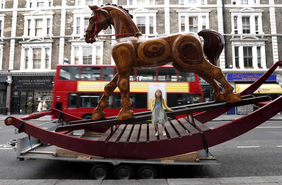 Riva Lemanski, 6 poses on a giant two-storey rocking horse outside Christie's auction house in London.
