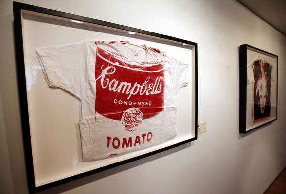 Artist Andy Warhol's 'Campbell's Tomato Soup' (L), a screen print on t-shirt, ca 1981 (estimate is $12,000 to 15,000) and 'Self-Portrait with Fright Wig' (R), a screen print on t-shirt, ca. 1986 (estimate is $15,000-20,000)  are seen on display at Christie's in New York City.