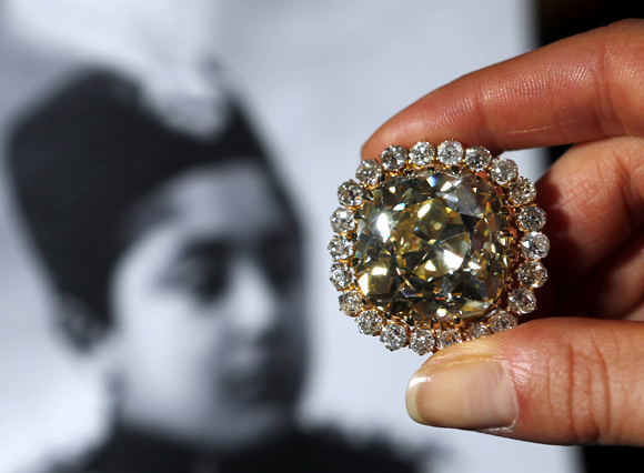 A Sotheby's staff member holds a fancy yellow 74.53 carat diamond and diamond jewel from the late 19th century during an auction preview in Geneva.