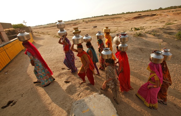 Women carry metal pitchers containing drinking water to their homes at Merta district in Rajasthan.
