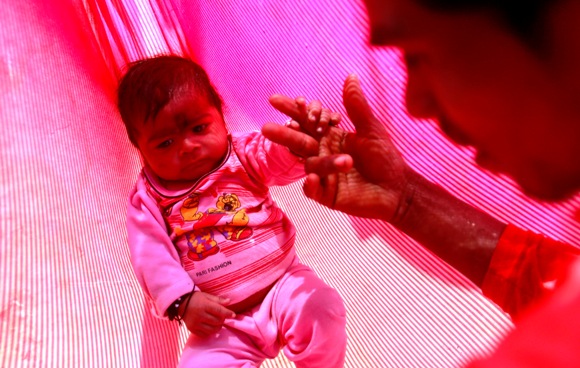 Gopal Kishan, 16, plays with his four-month-old baby Alok lying in a hammock, at his wife's house near Baran, Rajasthan.