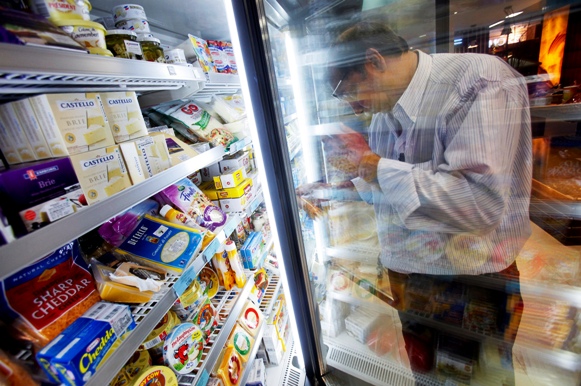 A customer examines a packet of cheese in the processed dairy food section of a supermarket in Mumbai.