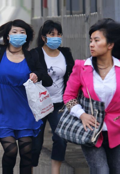 Women wearing face masks run to cross a street on a heavy haze day during winter in Beijing.
