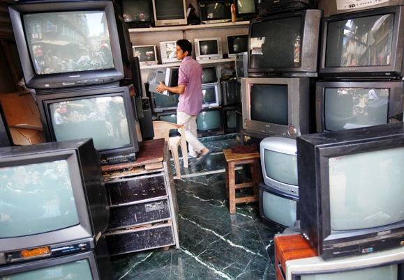 A shopkeeper carries a television inside a shop selling TV sets in Mumbai.