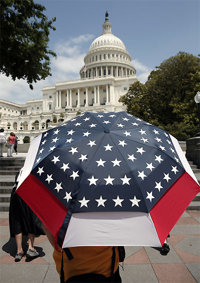 A guide for Chinese tourists shields himself from the sun with a stars and stripes umbrella on Capitol Hill in Washington.