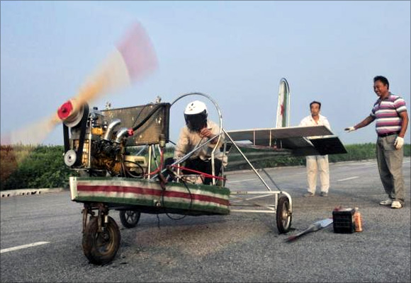 Ding Shilu (L) tests the engine of his home-made aircraft before conducting a test flight on the outskirts of Shenyang, Liaoning province.