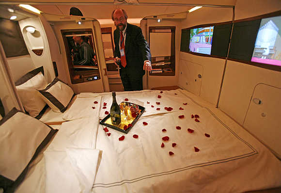 A journalist inspects a double bed in first-class suite.