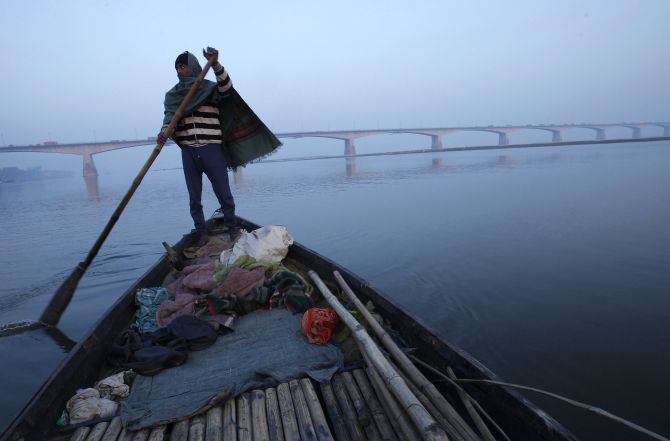 A man rows his boat in the waters of river Ganges with Mahatma Gandhi Setu bridge seen in the background in the eastern Indian city of Patna, in Bihar state.