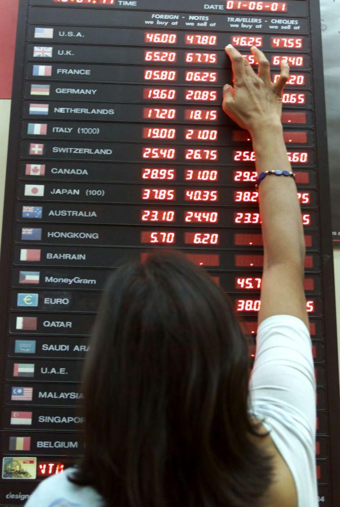 A woman checks the rupee-dollar exchange rate at a foreign exchange bureau.