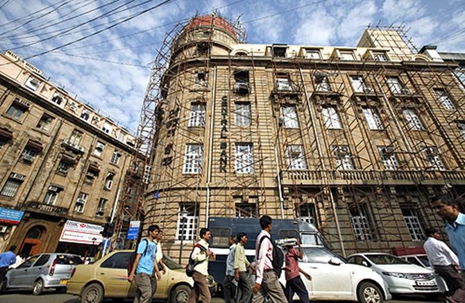 Commuters walk past the headquarters of Central Bank of India in Mumbai.