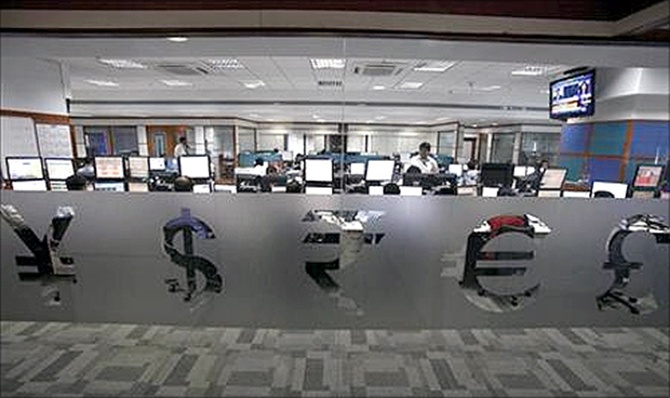 Foreign currency traders work inside a trading firm behind the signs of various world currencies, in Mumbai.
