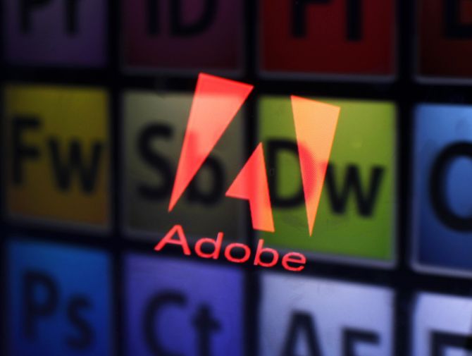 An Adobe logo and Adobe products are seen reflected on a monitor display.