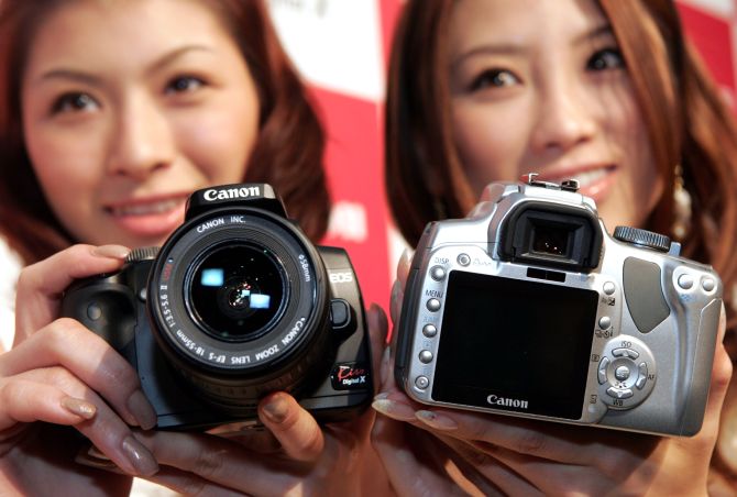 Models pose with Canon's EOS Kiss Digital X SLR camera, at the Canon headquarters in Tokyo.