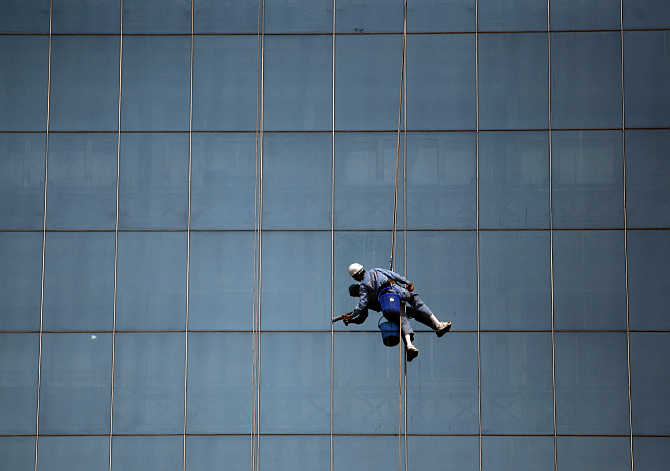 A worker cleans the glasses of a building in the commercial hub of New Delhi.