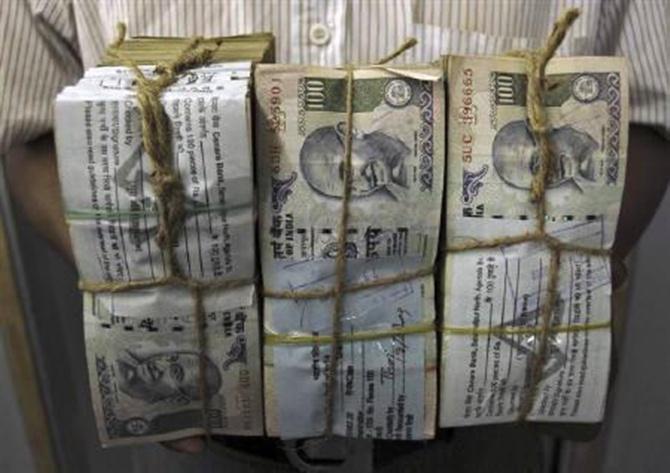 An employee carries bundles of rupee notes inside a bank in Agartala.