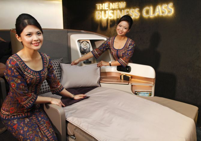 Singapore Airlines Ltd stewardesses pose next to a business class seat during the launch of their new generation of cabin products at Changi Airport in Singapore.