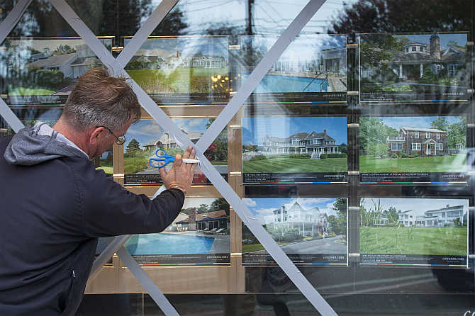 A man places duct tape on the windows of a real estate office in Westhampton Beach, New York.