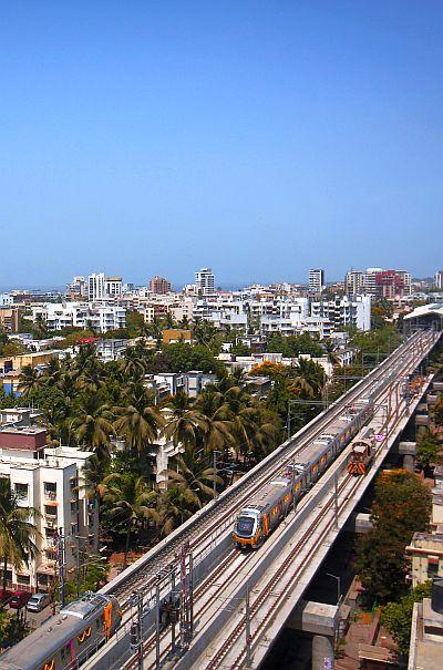 Metro trains pass through a residential area in Mumbai during its first official safety trial run.