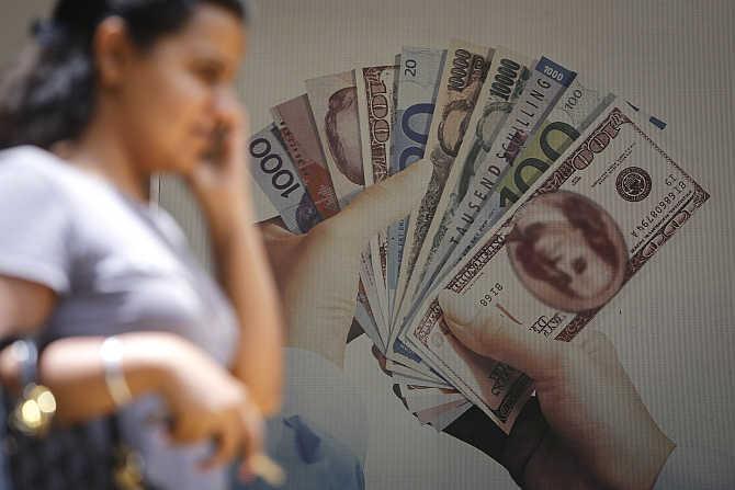 A customer walks past an advertisement for a foreign currency exchange facility at a bank in Mumbai.