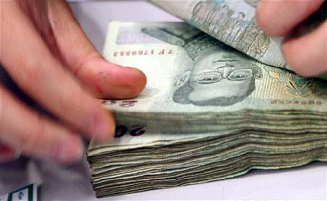 A teller counts 20 baht notes imprinted with the face of Thai King Bhumibol Adulyadej at a bank in Bangkok.