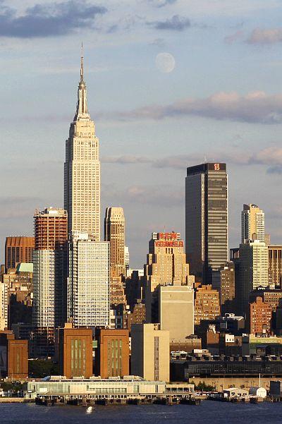 The moon rises next to the Empire State Building.