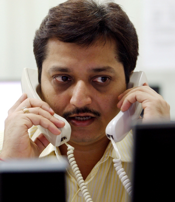 A trader speaks on phones while trading at a stock brokerage in Mumbai.