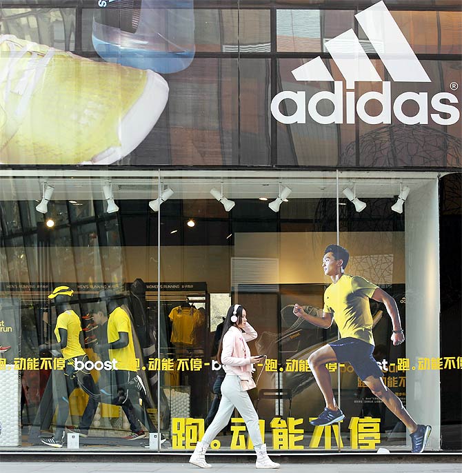 A woman walks past an Adidas shop at a shopping district in Beijing.