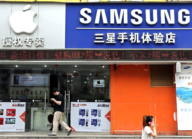 People walk past a mobile phone store selling Apple and Samsung products in Wuhan.