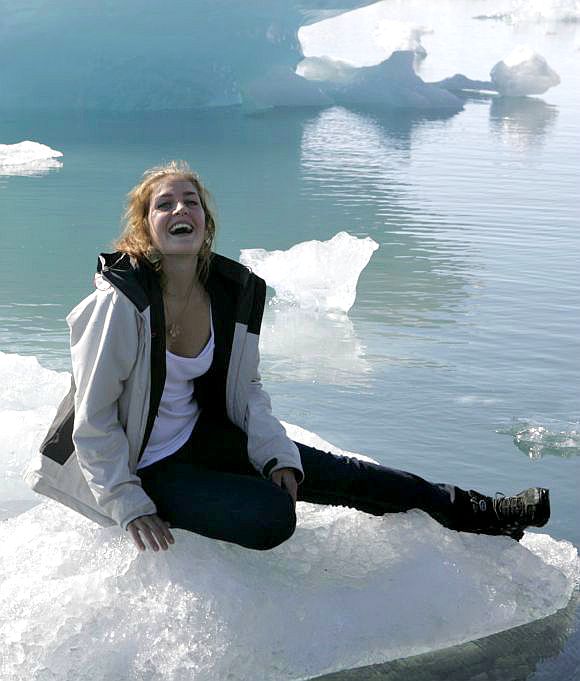 A woman poses on ice in southeast Iceland. The country has the least economic suffering.