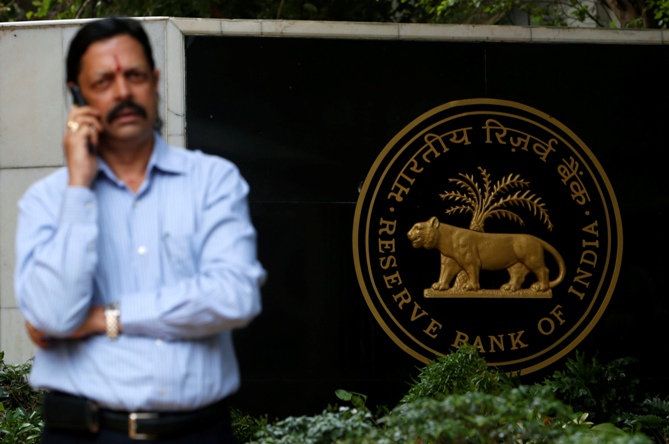 A man speaks on his mobile phone in front of the Reserve Bank of India seal at the RBI headquarters in Mumbai.