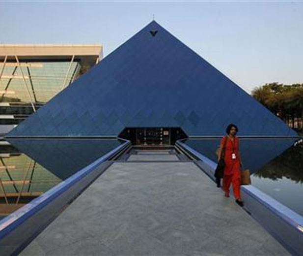 An employee walks out of an iconic pyramid-shaped building made out of glass in the Infosys campus at Electronics City in Bangalore.