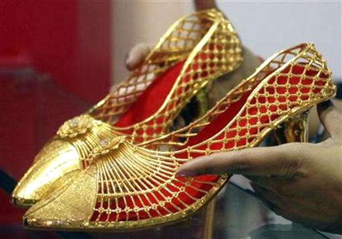  An employee displays a pair of gold footwear at the Gem and Jewellery India International Exhibition in Chennai.