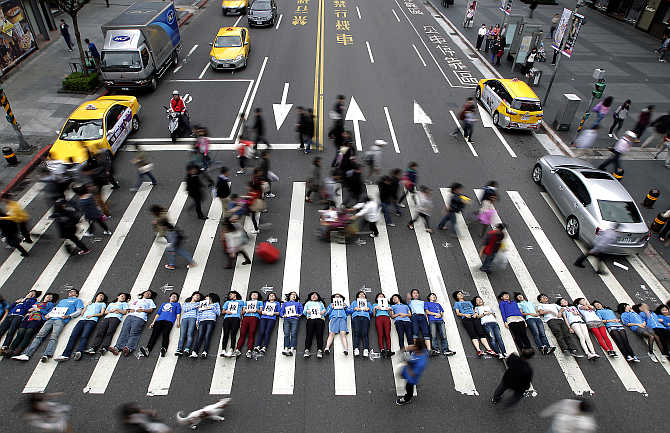 People lie on a pedestrian crossing during a flashmob event in a shopping area in Taipei, Taiwan.