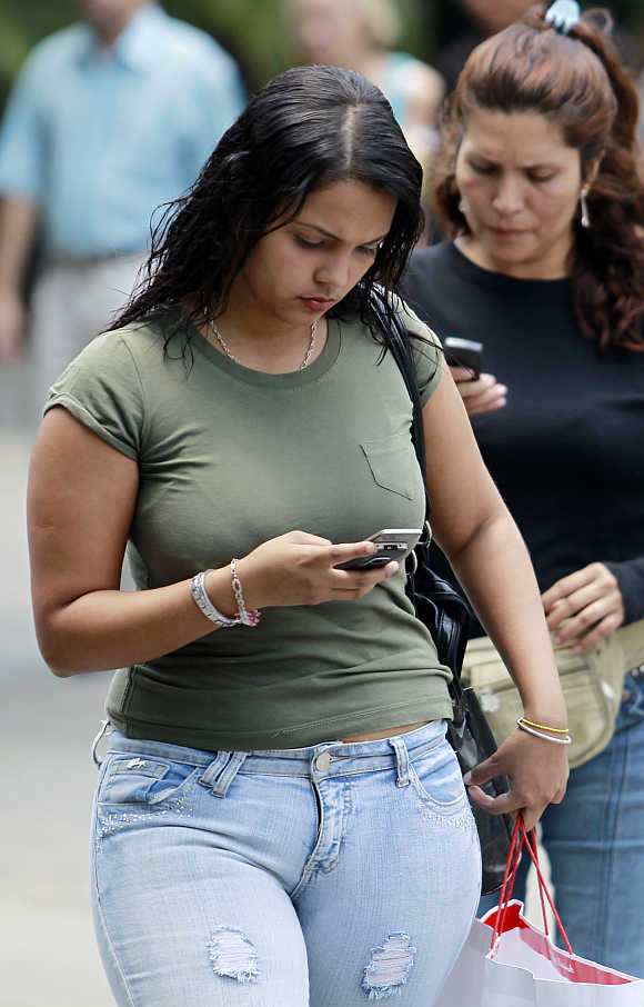 People use their mobile phones to surf Internet in Caracas, Venezuela.